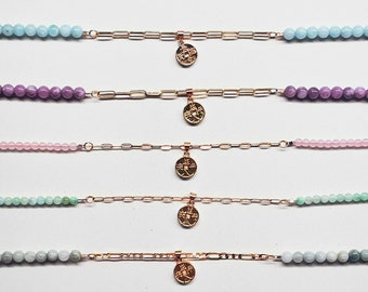 May include: Six gold chain bracelets with different colored beads and a gold charm. The charms are all the same design, a small circle with a design inside.