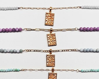 May include: Six gold necklaces with different colored beads and a gold pendant with a detailed design. The pendants are all the same design but are different sizes.