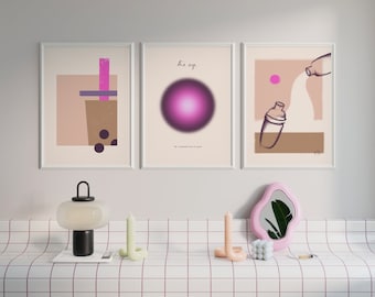 May include: Three framed illustrations with white frames and white mats. The illustrations are on a white background. The left illustration is a pink and brown abstract design with a pink and white striped straw and a cup with black boba pearls. The middle illustration is a pink and white abstract design with a pink circle and the text "the eye." The right illustration is a pink and brown abstract design with a white shaker pouring a white liquid into a glass with a pink circle.
