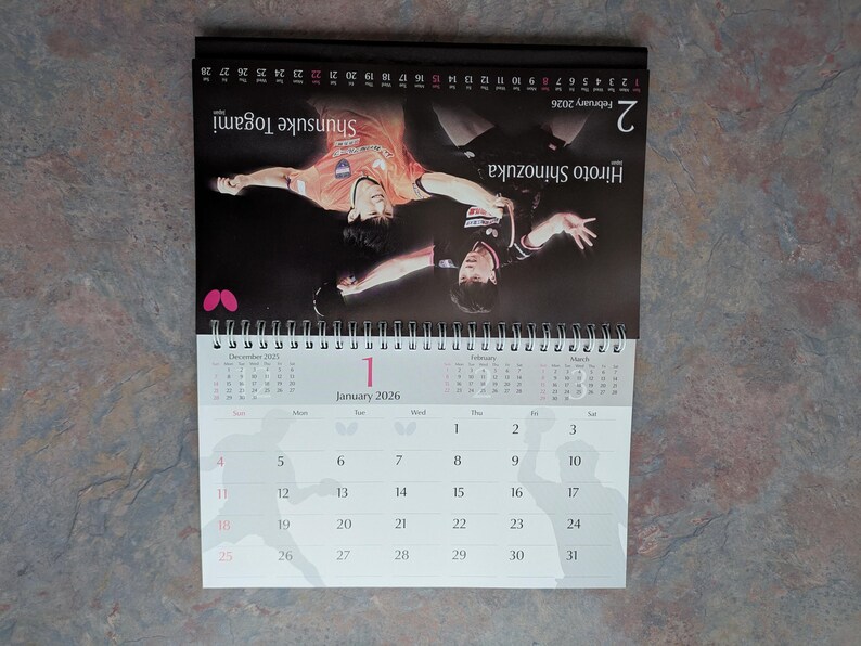 May include: A 2026 desk calendar featuring two table tennis players in action. The calendar shows the month of January with the date of the 1st highlighted. The calendar also shows the month of February with the date of the 2nd highlighted.