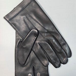 May include: A pair of black leather gloves with a snap closure on the wrist.