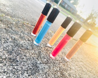 May include: Five clear lip gloss tubes with black caps. The lip glosses are in shades of red, blue, orange, pink, and brown.