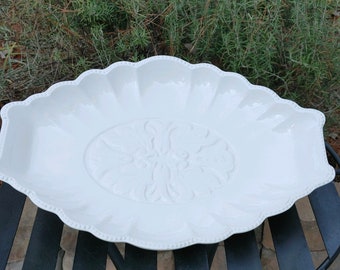 May include: White ceramic serving platter with a scalloped edge and a raised floral design in the center.
