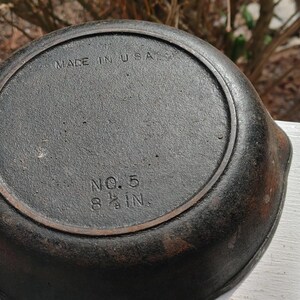 May include: A cast iron skillet with a black finish. The bottom of the skillet is marked "MADE IN USA" and "NO. 5 8 1/2 IN."