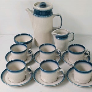 May include: A white and blue ceramic tea set with a teapot, creamer, sugar bowl, and six cups and saucers.