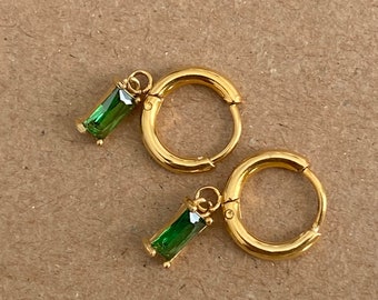 May include: Gold hoop earrings with a dangling green rectangular stone charm.