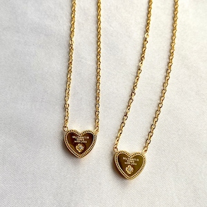 May include: Two gold necklaces with heart pendants. Each pendant features a small diamond and the inscription "My heart is filled with you".