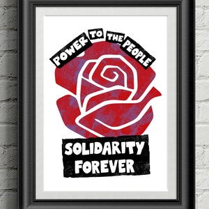 Può includere: Stampa artistica incorniciata con una grafica di rosa rossa e le parole "POWER TO THE PEOPLE" e "SOLIDARITY FOREVER" in bianco e nero. L'opera è incorniciata in nero, su un muro di mattoni bianchi.