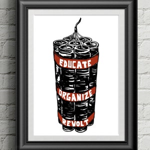 May include: Framed print featuring a bundle of dynamite with a red band. The band displays the words "EDUCATE, ORGANIZE, REVOLT" in white. The print is set against a white background and framed in black.