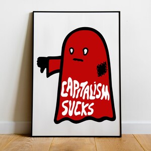 May include: A framed art print featuring a red ghost-like figure with a black thumb down and the words "CAPITALISM SUCKS" in white. The artwork has a minimalist design and is set against a white background.