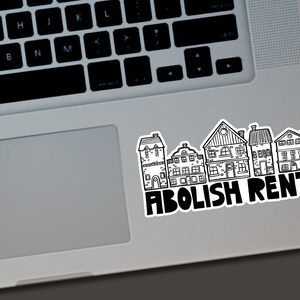 Puede incluir: Una pegatina en blanco y negro con una fila de casas estilizadas. La pegatina tiene las palabras "ABOLISH RENT" en letras negras en negrita. La pegatina est&aacute; colocada en un port&aacute;til plateado.