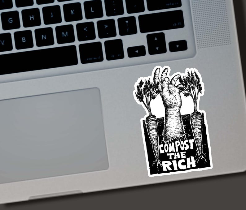 May include: Black and white sticker featuring a hand emerging from the ground between two carrots. The text "COMPOST THE RICH" is printed below the hand. The sticker is placed on a laptop.
