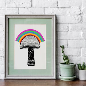 May include: A framed art print featuring a whimsical mushroom design with a rainbow arching over the cap. The mushroom has a black and white patterned cap and stem, with stars and other details. The frame is a light green color.