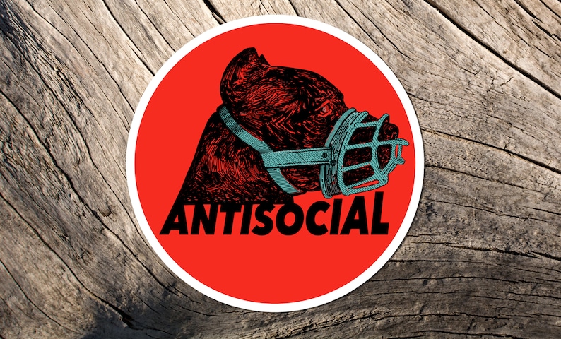 May include: A round sticker with a red background featuring a detailed illustration of a dog's head wearing a muzzle. The word "ANTISOCIAL" is printed in white below the dog.
