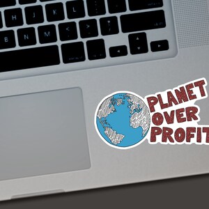 Puede incluir: Una pegatina blanca con una ilustraci&oacute;n de un globo terr&aacute;queo azul y blanco y el texto rojo "PLANET OVER PROFIT". La pegatina est&aacute; colocada en un port&aacute;til plateado.