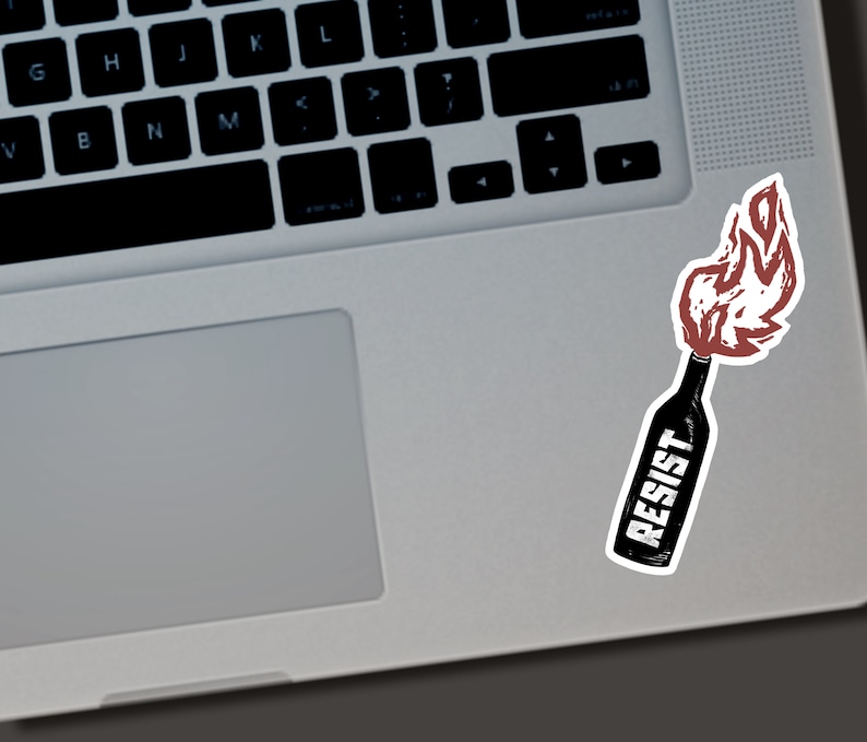 May include: A sticker featuring a stylized illustration of a Molotov cocktail. The bottle is black with the word "RESIST" in white lettering. The flames are red and white, suggesting a protest or resistance theme.