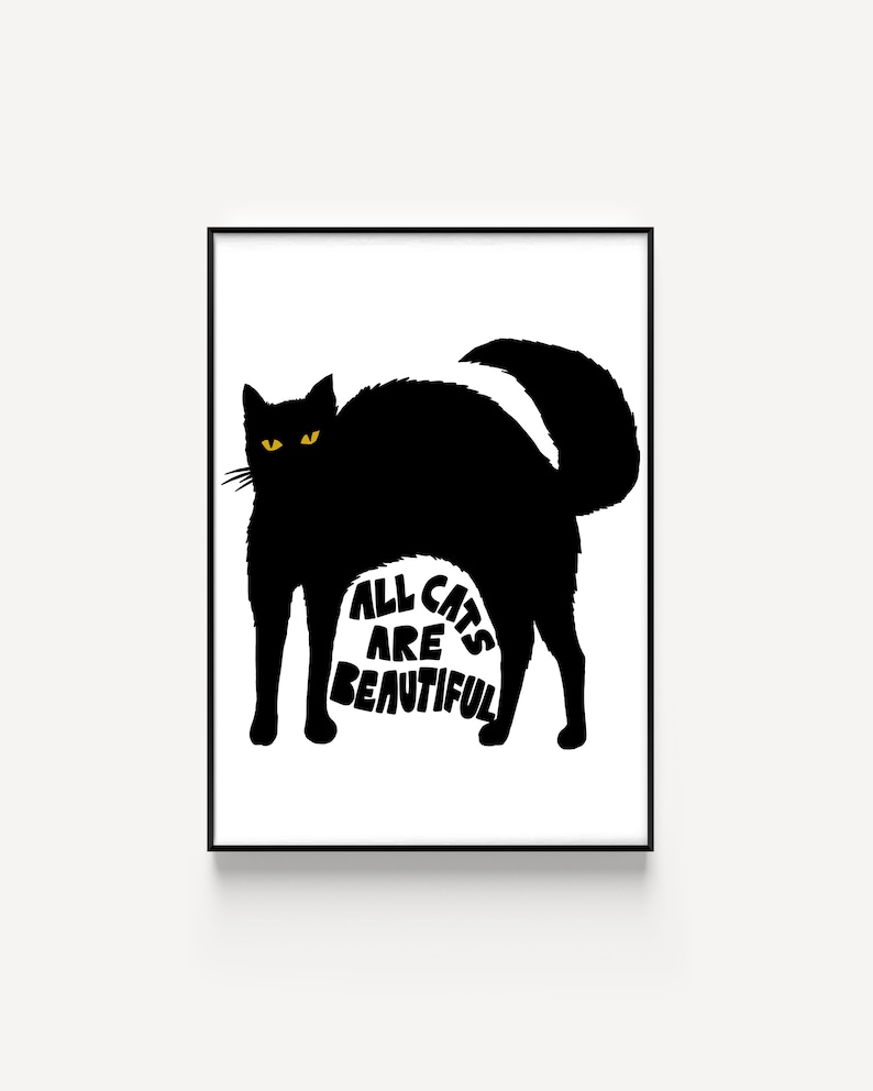 May include: A framed art print featuring a black cat silhouette with yellow eyes and the text "ALL CATS ARE BEAUTIFUL" in white. The cat is arched, with its tail up. The artwork is set against a white background.