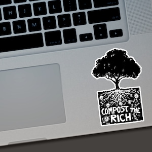 Puede incluir: Una pegatina en blanco y negro con un &aacute;rbol con ra&iacute;ces y el texto "COMPOST THE RICH". La pegatina est&aacute; colocada en un port&aacute;til plateado.