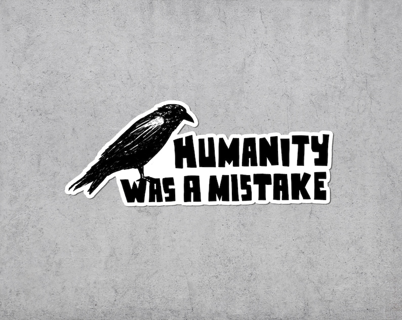 May include: A black and white sticker featuring a detailed illustration of a crow perched above the text "HUMANITY WAS A MISTAKE" in bold, block letters. The sticker has a white border and is set against a gray background.