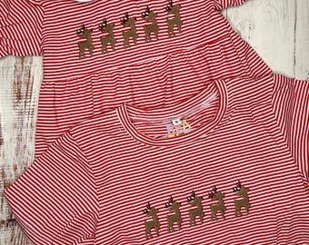 May include: Two red and white striped dresses with a line of reindeer embroidered on the front. The dress on top has a white Peter Pan collar.