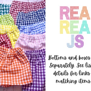 May include: A set of ten gingham shorts in various colours, including red, blue, yellow, green, orange, and purple. The shorts are all made of a lightweight fabric and have a checkered pattern. The text "REA REA JS" is visible in the background.