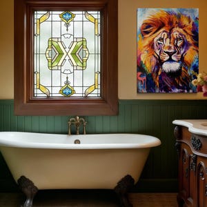 Puede incluir: Una ba&ntilde;era blanca con patas de garra se encuentra en un ba&ntilde;o con lambr&iacute;n verde y una ventana de vidriera. Un cuadro colorido de la cabeza de un le&oacute;n cuelga de la pared sobre un tocador de madera con una encimera blanca.