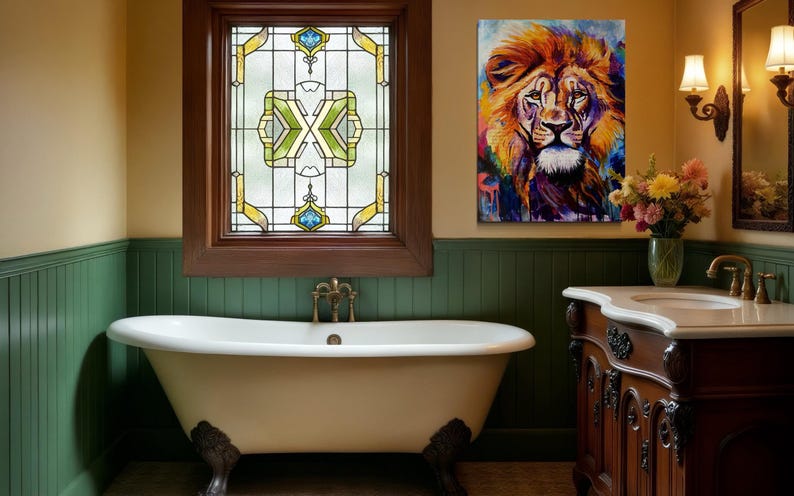 Puede incluir: Una ba&ntilde;era blanca con patas de garra se encuentra en un ba&ntilde;o con lambr&iacute;n verde y una ventana de vidriera. Un cuadro colorido de la cabeza de un le&oacute;n cuelga de la pared sobre un tocador de madera con una encimera blanca.