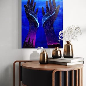 May include: A painting of two hands reaching up towards a blue sky with stars. The hands are filled with stars and the sky is a deep blue. The painting is on a canvas and is framed.