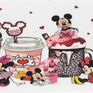 Peut inclure: Fond blanc avec des illustrations de dessins animés de Mickey et Minnie Mouse avec des friandises sur le thème de la Saint-Valentin. L'image comprend diverses tasses et mugs décorés de cœurs, de nœuds et des personnages emblématiques. Des cœurs rouges éparpillés ajoutent au design festif.