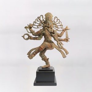 May include: A bronze statue of a Hindu deity with multiple arms, wearing a crown and holding various objects, including a trident and a sword. The statue is standing on a black base.