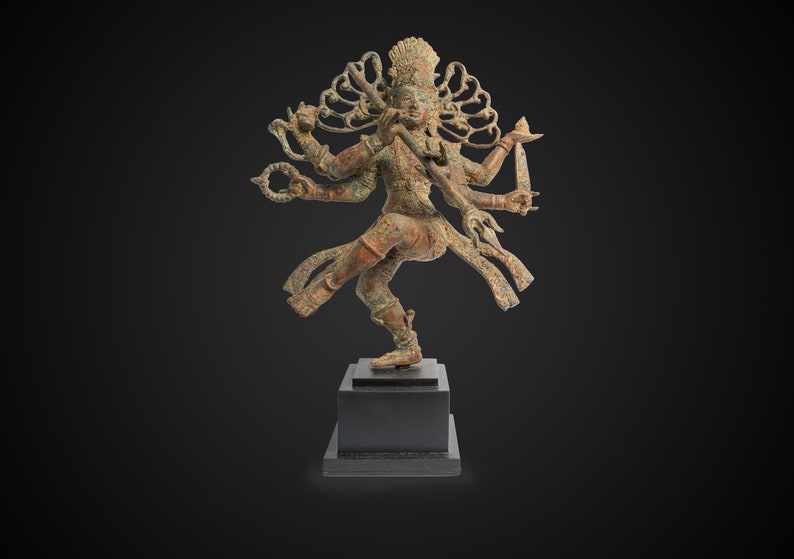 May include: A bronze sculpture of a multi-armed deity in a dancing pose. The deity has a crown and is adorned with intricate details. The sculpture is on a black wooden base.