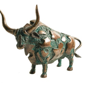 May include: A bronze sculpture of a bull with a textured, green patina finish. The bull's horns are raised and its head is tilted down. The sculpture is detailed with a rough, textured surface.
