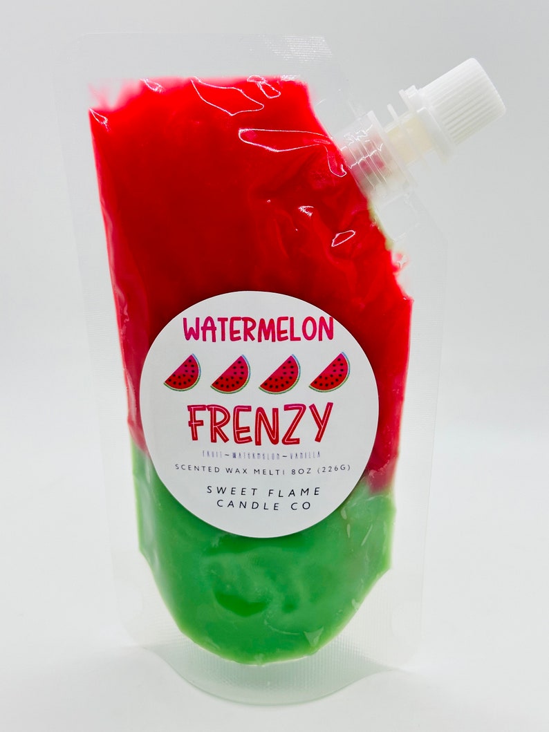 Op de afbeelding: Een doorzichtige plastic zak gevuld met rode en groene geurwax. De zak heeft een tuit voor gemakkelijk gieten. Het etiket luidt "Watermelon Frenzy" met drie watermeloenplakjes en de tekst "Scented Wax Melt 8 oz (226g) Sweet Flame Candle Co."