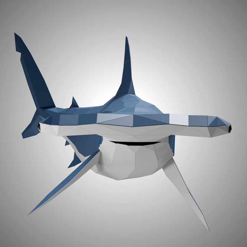 May include: A low-poly hammerhead shark sculpture featuring a geometric design with sharp, angular facets. The shark is colored in shades of deep blue on the dorsal side and white on the ventral side, showcasing a distinct wide, flat head shape.
