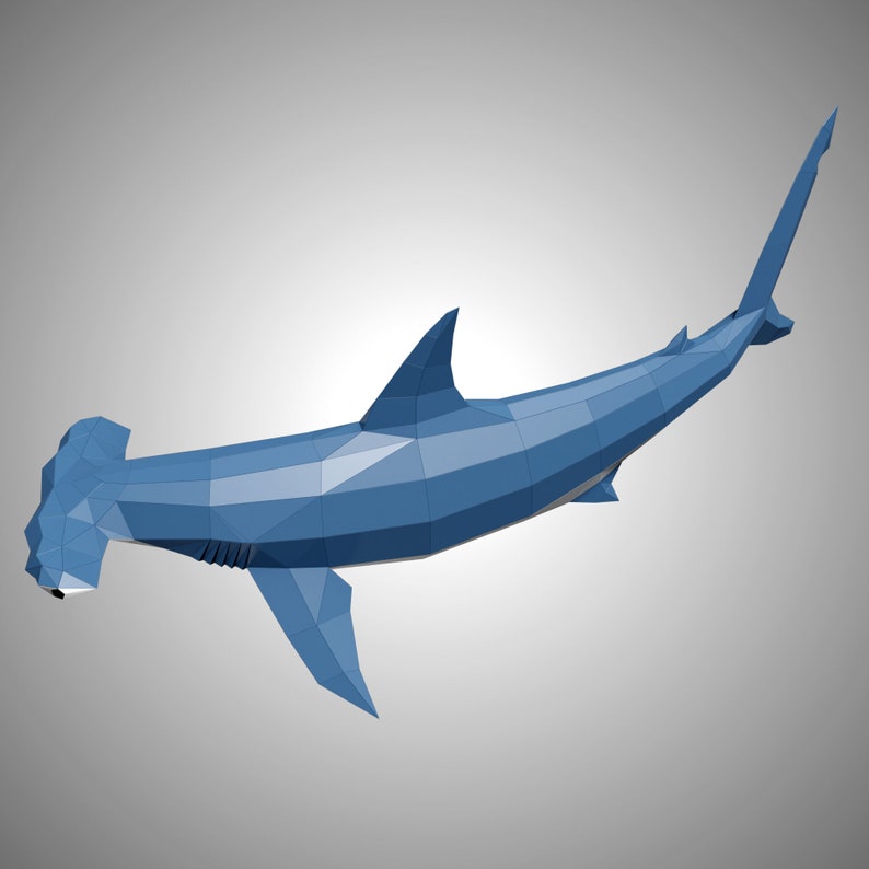 May include: A low-poly, geometric hammerhead shark sculpture rendered in shades of blue. The figure features a distinct wide, flattened head, a prominent dorsal fin, and a streamlined body composed of multiple triangular facets and sharp edges.