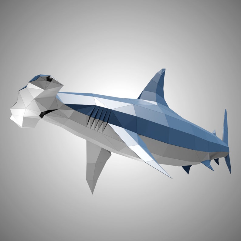 May include: A low-poly geometric sculpture of a hammerhead shark. The figure is constructed from flat, triangular facets in shades of blue, gray, and white, creating a sharp, angular appearance that defines the shark's body, fins, and head.