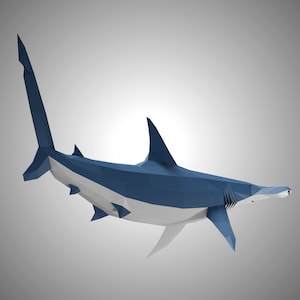 May include: A low-poly geometric sculpture of a hammerhead shark. The shark features a dark blue upper body and a white underbelly, constructed from flat triangular facets that create a sharp, angular, and modern digital aesthetic.