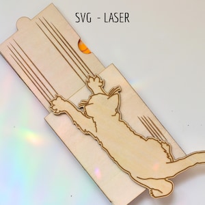 May include: A light-colored wooden sliding box featuring a laser-cut design of a cat reaching upward with its paws, creating four long scratch marks on the lid. The text SVG - LASER is printed in black at the top of the wooden surface.