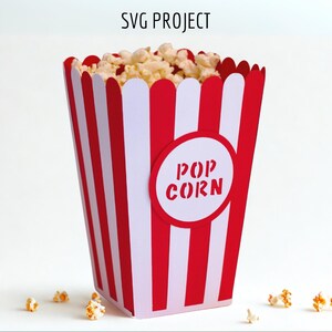May include: A red and white striped popcorn box with the words "POP CORN" in a circle on the front. The box is filled with popcorn.