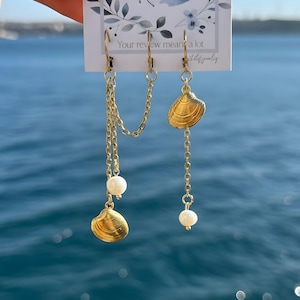 May include: A white ceramic mug with a black handle and the text "But First, Coffee" in a bold, black font. The mug is set against a blurred background. The mug appears to be approximately 10 cm tall.