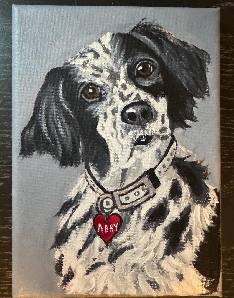 May include: A painted portrait of a dog with black and white fur, brown eyes, and a red heart-shaped tag that says "Abby." The dog is wearing a collar. The background is a light gray.