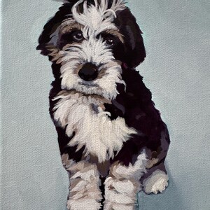 May include: A painted portrait of a puppy with black, white, and brown fur, sitting against a light blue background. The puppy has a fluffy white patch on its head and a dark nose. The artwork is a close-up of the dog.