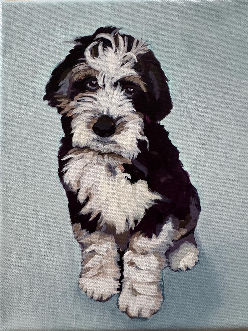 May include: A painted portrait of a puppy with black, white, and brown fur, sitting against a light blue background. The puppy has a fluffy white patch on its head and a dark nose. The artwork is a close-up of the dog.