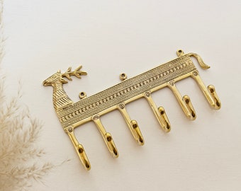 May include: Gold metal deer head key holder with six hooks. The deer head is detailed with an intricate pattern.