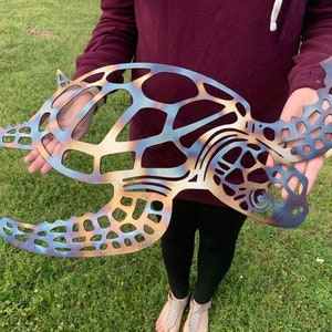 May include: A metal sea turtle wall art with a blue, orange, and brown color scheme. The turtle is cut out in a detailed design and has a textured finish.