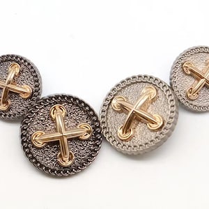 May include: Three round, decorative buttons with a textured, metallic finish. Each button features a gold-colored cross design with a raised, stitched effect.