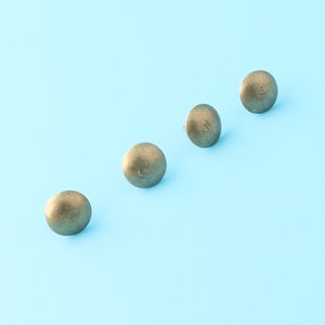 May include: Four gold-colored tacks on a light blue background.