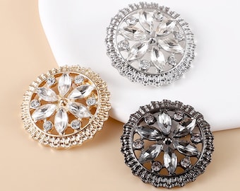 May include: Three decorative buttons with a flower design. The buttons are silver, gold, and black.