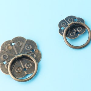 Può includere: Due tiretti per cassetti in bronzo in stile antico con disegni floreali decorativi e maniglie ad anello.