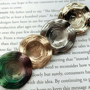 May include: Four decorative round plates with a swirling pattern. The plates are in shades of gold, silver, green, and brown.